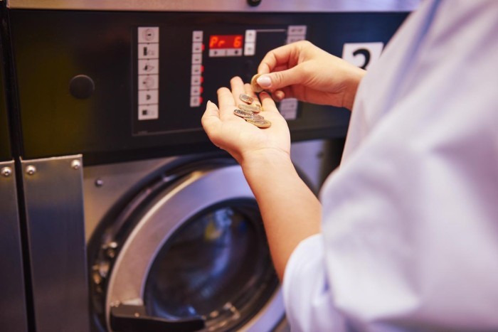 A lady putting coins into a washing machine