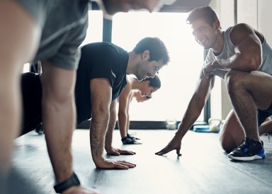Trainer encourages gym members in plank position