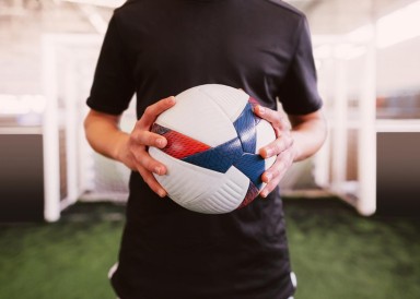 Man holding a football in front of a goal