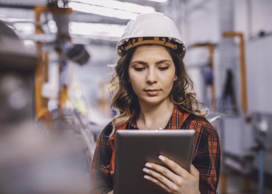 Woman on a construction site wearing a hard hat and looking at a tablet device